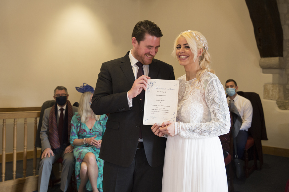 Bride and Groom proudly holding wedding certificate during wedding ceremony at Archbishop's Palace in Maidstone, Kent.