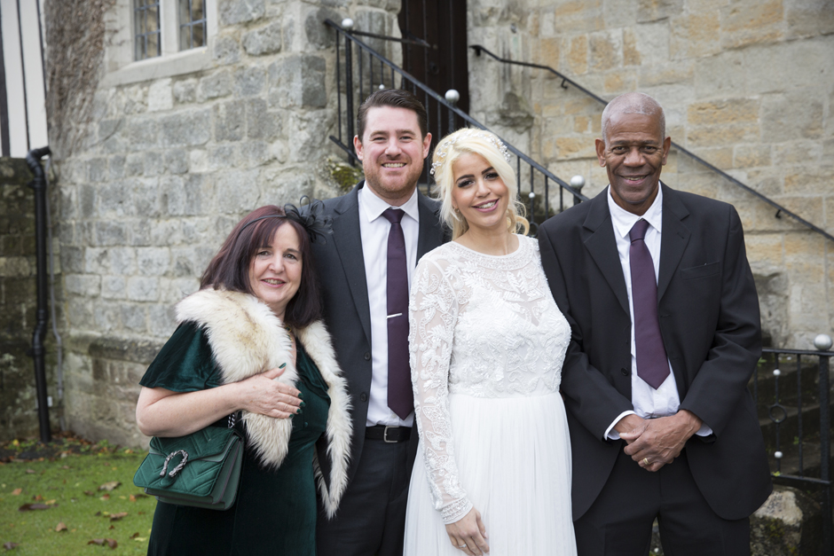Bride & Groom standing with Bride's Parents outside Archbishop's Palace in Maidstone, Kent. Captured by Kent wedding photographer, Victoria Green.