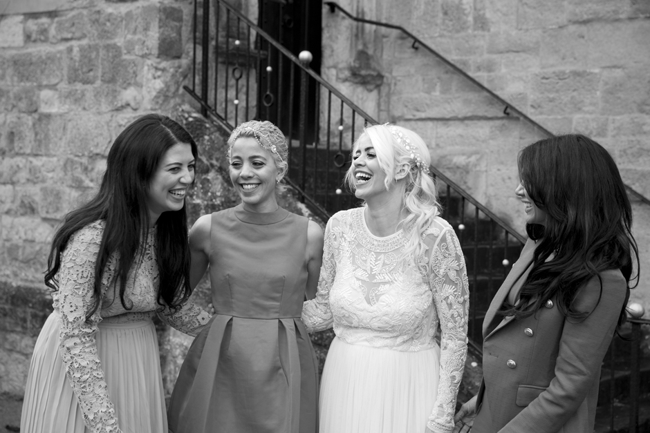 Black and white - Bride laughing with her sisters outside Archbishop's Palace in Maidstone, Kent. Captured by Kent based wedding photographer, Victoria Green.