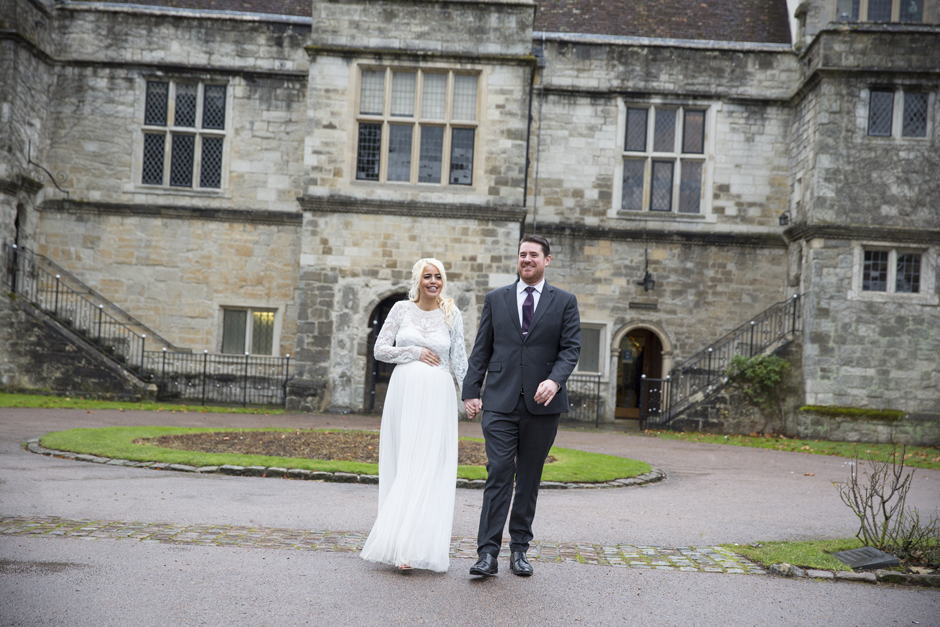 Bride and Groom holding hands and walking in front of Archbishop's Palace in Maidstone, Kent. Captured by Victoria Green Photography.