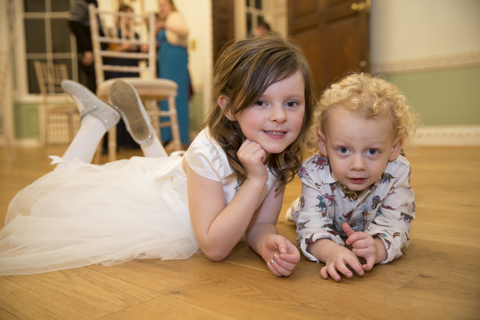 Flower girl and little boy laying on their tummies at Bradbourne House wedding reception at East Malling, Kent.
