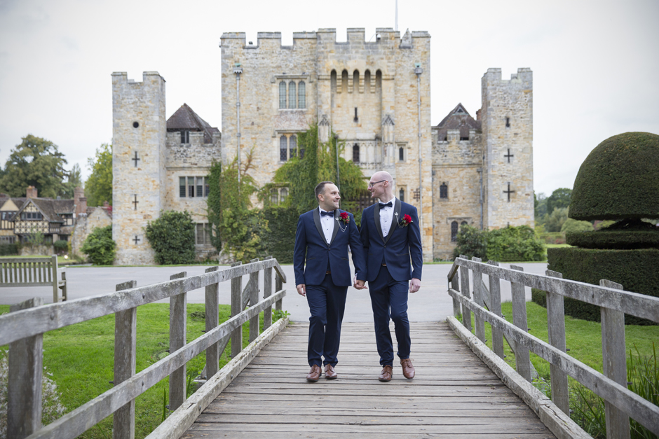 Grooms looking at each other walking over bride at Hever Castle wedding in Kent. Captured by Kent wedding photographer Victoria Green.