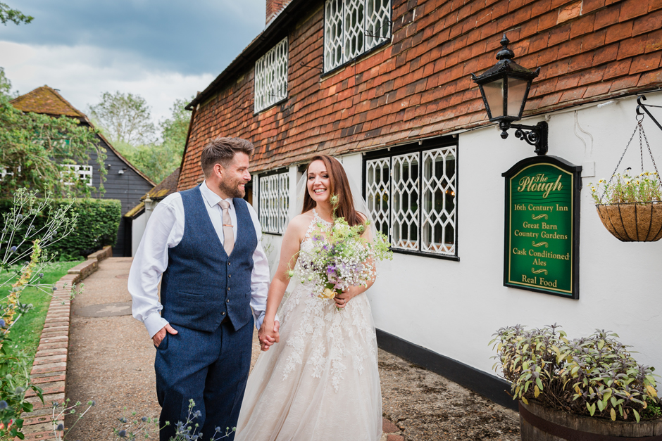 Bride and Groom holding hands, looking at each other and walking at the front of the Plough & Barn at Leigh